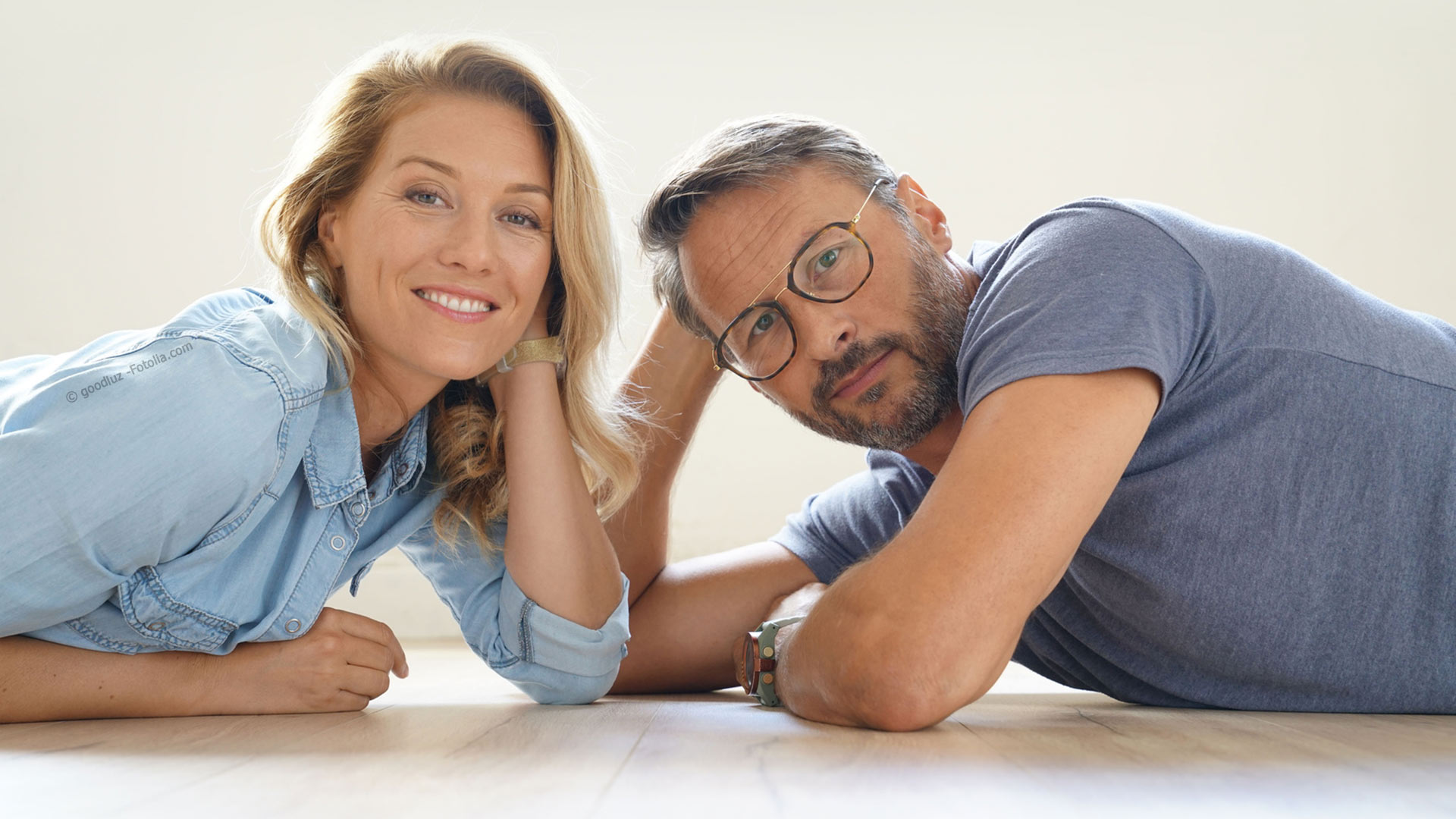 Smiling Mature Couple Day Dreaming While Sitting On Floor